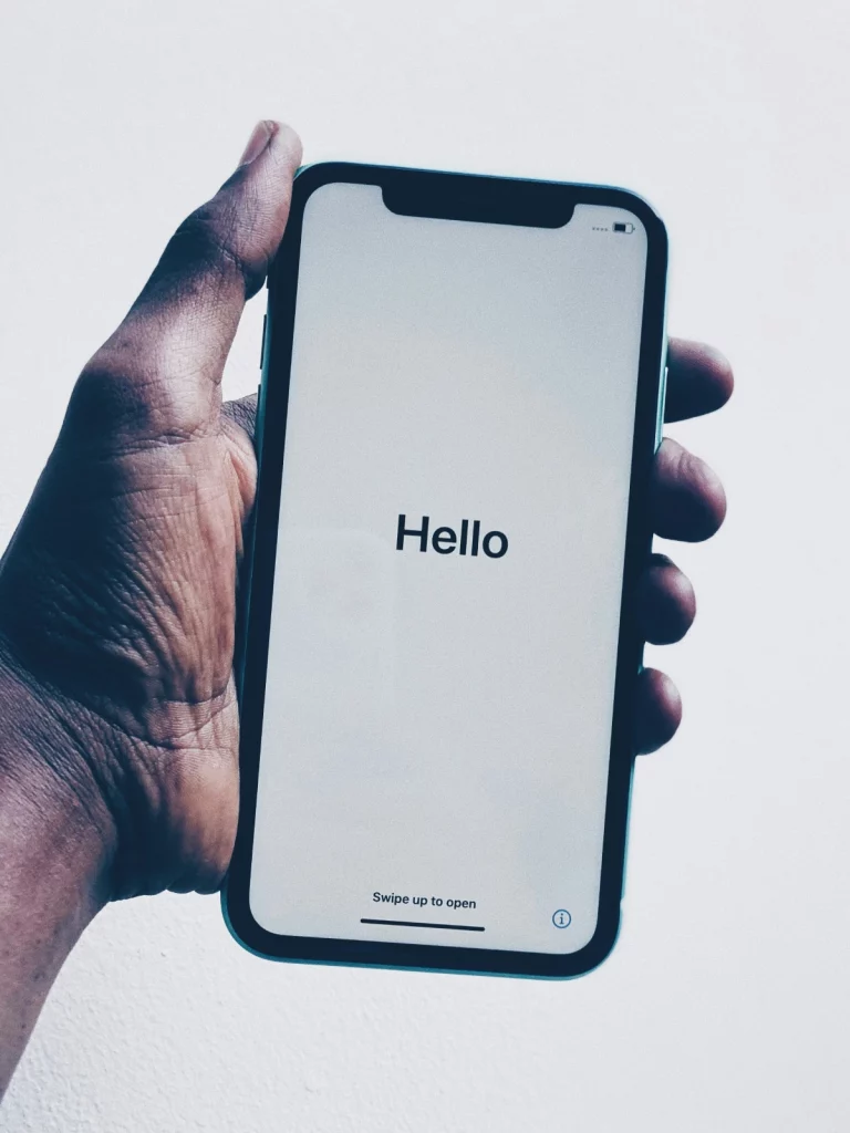 Una mano sostiene un teléfono inteligente con la pantalla de bienvenida "Hola"